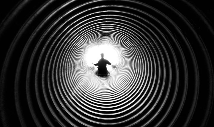 grayscale photography of person at the end of tunnel